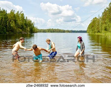 Stock Image - The group of the friends chilling out on the beach, summer day. Shot in southern Finland.. Fotosearch