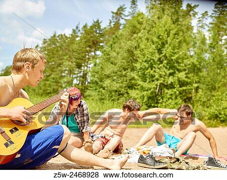 The group of the friends chilling out on the beach, summer day. Shot in southern Finland. View Large Photo Image Stock Photo - The group of the friends chilling out on the beach, summer day. Shot in southern Finland.. Fotosearch