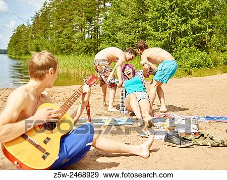Stock Photo - The group of the friends chilling out on the beach, summer day. Shot in southern Finland.. Fotosearch