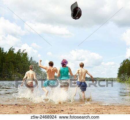 Picture - The group of the people runs in the lake, summer day. Shot in southern Finland.. Fotosearch