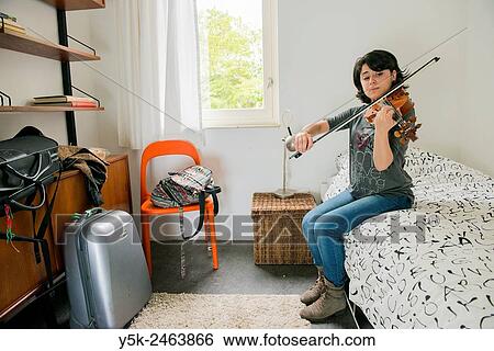 Tilburg, Netherlands. Female Italian violinist sitting on the bed of her Airbnb guest room, while practising with her violin. View Large Photo Image Stock Photograph - Tilburg, Netherlands. Female Italian violinist sitting on the bed of her Airbnb guest room, while practising with her violin.. Fotosearch
