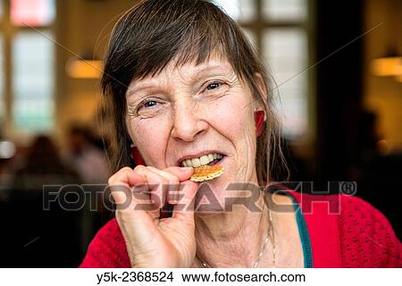 Tilburg, Netherlands. Portrait of a 61 year old colorful dressed and fashionable woman preparing for lunch in a daytime cafe-restaurant. View Large Photo Image Picture - Tilburg, Netherlands. Portrait of a 61 year old colorful dressed and fashionable woman preparing for lunch in a daytime cafe-restaurant.. Fotosearch