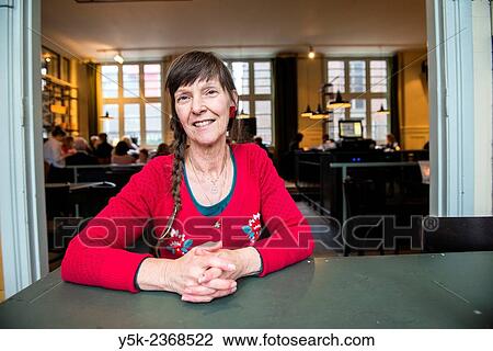 Tilburg, Netherlands. Portrait of a 61 year old colorful dressed and fashionable woman preparing for lunch in a daytime cafe-restaurant. View Large Photo Image Stock Image - Tilburg, Netherlands. Portrait of a 61 year old colorful dressed and fashionable woman preparing for lunch in a daytime cafe-restaurant.. Fotosearch