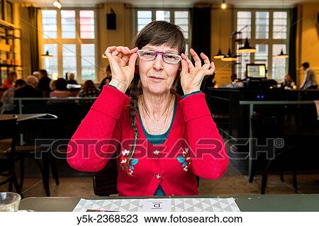 Tilburg, Netherlands. Portrait of a 61 year old colorful dressed and fashionable woman preparing for lunch in a daytime cafe-restaurant. View Large Photo Image Stock Image - Tilburg, Netherlands. Portrait of a 61 year old colorful dressed and fashionable woman preparing for lunch in a daytime cafe-restaurant.. Fotosearch