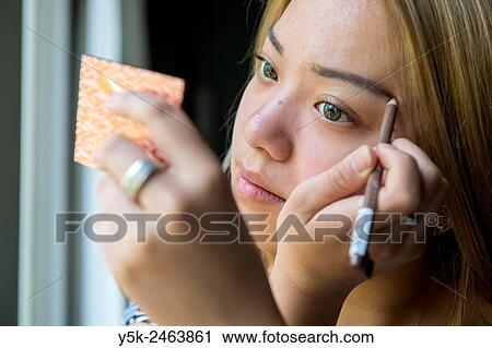 Tilburg, Netherlands. Studio portrait of a young Chinese girl doing her make up. View Large Photo Image Stock Image - Tilburg, Netherlands. Studio portrait of a young Chinese girl doing her make up.. Fotosearch