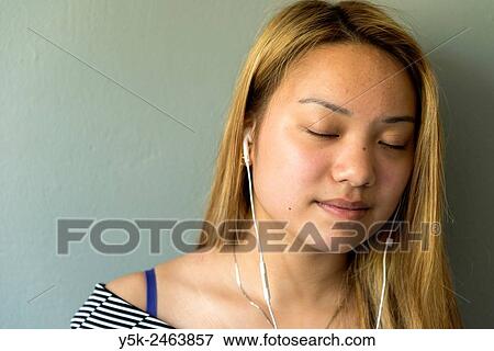 Tilburg, Netherlands. Studio portrait of a young Chinese girl with headphones in front of a grey background. View Large Photo Image Stock Photo - Tilburg, Netherlands. Studio portrait of a young Chinese girl with headphones in front of a grey background.. Fotosearch