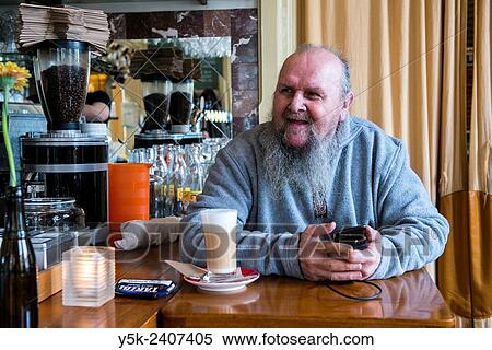 Tilburg, Netherlands. The 67 year old Kees, sitting at his regular spot at the bar of Grand Cafe Spaarbank, while having a large cup of Coffee Latte. View Large Photo Image Stock Photography - Tilburg, Netherlands. The 67 year old Kees, sitting at his regular spot at the bar of Grand Cafe Spaarbank, while having a large cup of Coffee Latte.. Fotosearch