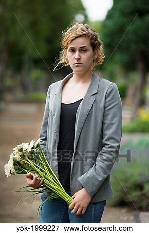 Tilburg, Netherlands. Young woman, holding flowers, before her visit to e deceases person, on a local cemetery. View Large Photo Image Stock Photo - Tilburg, Netherlands. Young woman, holding flowers, before her visit to e deceases person, on a local cemetery.. Fotosearch