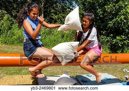 Two Sisters Having A Pillow Fight, Kingston Village Fete, Kingston, Sussex, UK. View Large Photo Image Stock Image - Two Sisters Having A Pillow Fight, Kingston Village Fete, Kingston, Sussex, UK.. Fotosearch