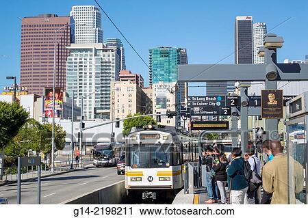 Stock Image - USA, California, Los Angeles, LA County Metro Rail, Gold Line, Pico Station, Commuters on Flower Street with TCW Tower and Pelli Tower in background. Fotosearch
