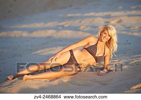 Young blond woman lying on a sandy beach in summer. View Large Photo Image Picture - Young blond woman lying on a sandy beach in summer.. Fotosearch