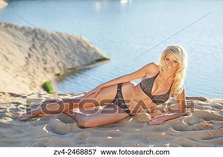 Young blond woman lying on a sandy beach in summer. View Large Photo Image Stock Photo - Young blond woman lying on a sandy beach in summer.. Fotosearch