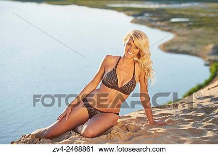 Young blond woman sitting on a sandy beach in summer. View Large Photo Image Stock Image - Young blond woman sitting on a sandy beach in summer.. Fotosearch