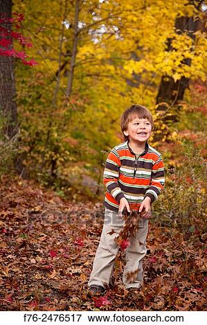 Stock Photo - 3 year old boy playing with autumn leaves... Fotosearch