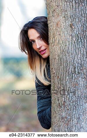 30 year old brunette woman peaking around a tree looking at the camera. View Large Photo Image Stock Photo - 30 year old brunette woman peaking around a tree looking at the camera.. Fotosearch