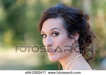 36 year old brunette woman outdoors looking over her shoulder directly at the camera. View Large Photo Image Stock Photo - 36 year old brunette woman outdoors looking over her shoulder directly at the camera.. Fotosearch