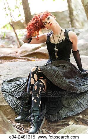 A 23 year old red head woman looking away from the camera in a long black dress, sitting on a path in a forest setting. View Large Photo Image Stock Photography - A 23 year old red head woman looking away from the camera in a long black dress, sitting on a path in a forest setting.. Fotosearch