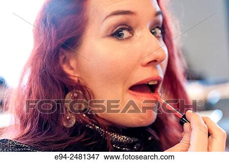A 37 year old redheaded woman applying lip gloss looking at the camera. View Large Photo Image Stock Photo - A 37 year old redheaded woman applying lip gloss looking at the camera.. Fotosearch
