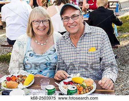 Stock Photography - a couple eat dinner outdoors at a wedding.. Fotosearch