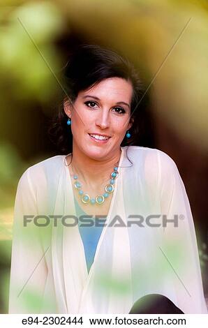 A portrait of a smiling 36 year old brunette woman looking directly at the camera, outdoors. View Large Photo Image Picture - A portrait of a smiling 36 year old brunette woman looking directly at the camera, outdoors.. Fotosearch