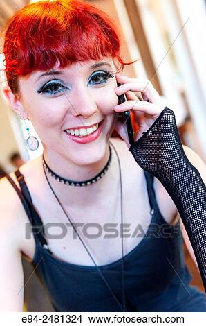 A smiling 23 year old red head woman talking on a cell phone and looking at the camera in a restaurant. View Large Photo Image Picture - A smiling 23 year old red head woman talking on a cell phone and looking at the camera in a restaurant.. Fotosearch