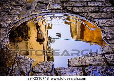 Stock Photo - After watering, water stagnates in a manhole cover in the neighborhood of El Carme, Valencia, Spain.. Fotosearch