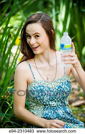 An 18 year old woman holding a bottle of water and smiling at the camera. View Large Photo Image Stock Image - An 18 year old woman holding a bottle of water and smiling at the camera.. Fotosearch
