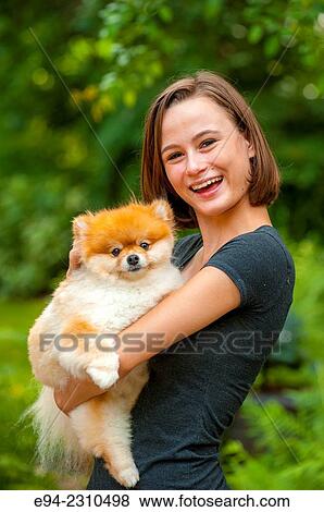 An 18 year old woman holding a Pomeranian dog and looking at the camera. View Large Photo Image Stock Photo - An 18 year old woman holding a Pomeranian dog and looking at the camera.. Fotosearch