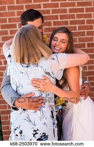an older woman hugs a bride and groom on their wedding day. View Large Photo Image Stock Image - an older woman hugs a bride and groom on their wedding day.. Fotosearch