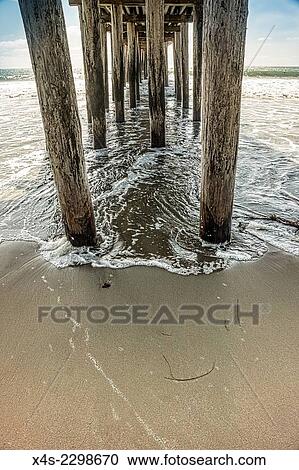 As the tide rises waves wash onto the sand beneath a wooden pier. View Large Photo Image Stock Image - As the tide rises waves wash onto the sand beneath a wooden pier.. Fotosearch