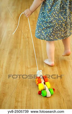 Baby girl pulling a wooden toy. View Large Photo Image Stock Photo - Baby girl pulling a wooden toy.. Fotosearch