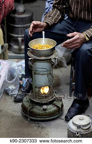 Stock Image - Bazari sitting in front of his meal prepared on a small oven, Bazar-e Bozorg in Esfahan, Isfahan, Iran, Asian.. Fotosearch
