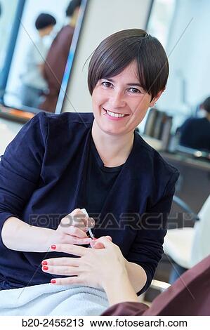 Stock Image - Beautician painting nails a woman. Manicure. Hairdressing salon and Beauty Clinic.. Fotosearch