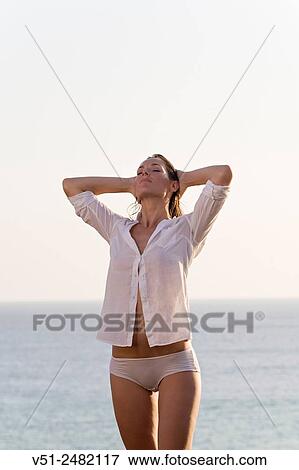 Stock Photo - Beautiful brunette woman stretching by the sea. Fotosearch