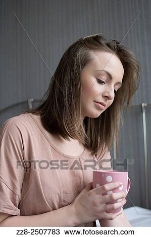 Stock Image - Beautiful woman having coffee in bed.. Fotosearch
