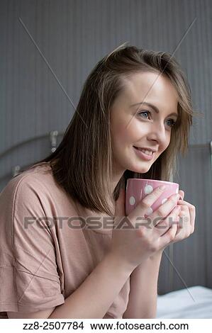 Beautiful young woman drinking coffee looking away. View Large Photo Image Picture - Beautiful young woman drinking coffee looking away.. Fotosearch