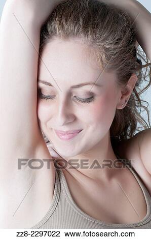 Stock Image - Beautiful young woman looking at armpit smiling.. Fotosearch