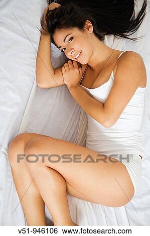 Stock Photograph - Brunette woman lying down in bed. Fotosearch