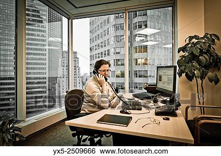 Business woman executive in a corner office sitting at the desk. View Large Photo Image Stock Photograph - Business woman executive in a corner office sitting at the desk.. Fotosearch