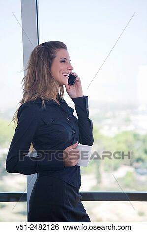Businesswoman with coffee and phone by the window View Large Photo Image Stock Photograph - Businesswoman with coffee and phone by the window. Fotosearch