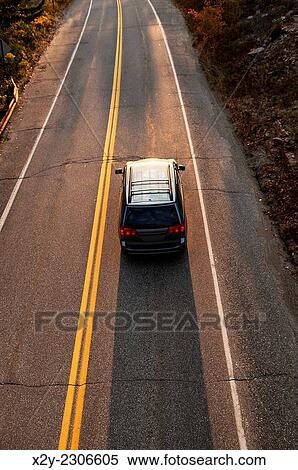 Car traveling along a road at sunset, Maine, USA. View Large Photo Image Stock Photography - Car traveling along a road at sunset, Maine, USA.. Fotosearch