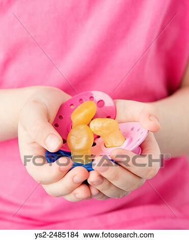 Close up of child hands holding three pacifiers. Little girl showing her dummy collection. View Large Photo Image Picture - Close up of child hands holding three pacifiers. Little girl showing her dummy collection.. Fotosearch
