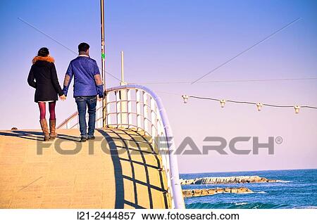 Couple walking on a bridge near the sea. Barcelona, Catalonia, Spain. View Large Photo Image Stock Photo - Couple walking on a bridge near the sea. Barcelona, Catalonia, Spain.. Fotosearch