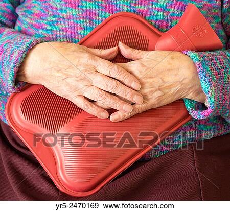 Elderly woman holding hot water bottle. England, UK. View Large Photo Image Stock Photo - Elderly woman holding hot water bottle. England, UK.. Fotosearch