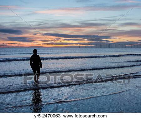 Female jogger cooling down in sea at sunrise with Teesside Offshore Windfarm in distance. Seaton Carew beach, north east England, United Kingdom, Europe. View Large Photo Image Stock Image - Female jogger cooling down in sea at sunrise with Teesside Offshore Windfarm in distance. Seaton Carew beach, north east England, United Kingdom, Europe.. Fotosearch
