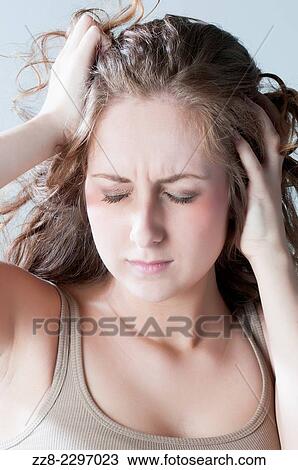 Stock Image - Frustrated young woman head in hands.. Fotosearch