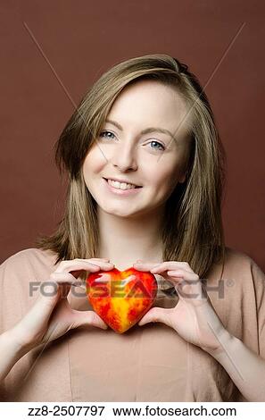 Stock Photo - Happy young woman holding a marble heart smiling.. Fotosearch