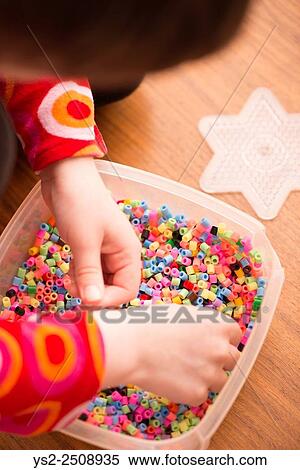 Little girl (5 years) playing with colorful plastic beads. A moment of childhood fun and leisure. View Large Photo Image Stock Photography - Little girl (5 years) playing with colorful plastic beads. A moment of childhood fun and leisure.. Fotosearch