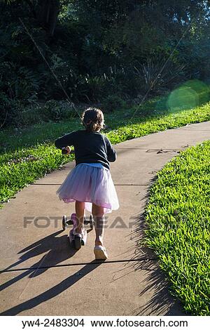 Little girl riding on her scooter in a park, Sydney, Australia. View Large Photo Image Picture - Little girl riding on her scooter in a park, Sydney, Australia.. Fotosearch