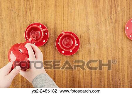 Little girl serving from tea pot at teaparty. Top view of cups and hands of child. The image shows an adorable moment of innocent childhood play. View Large Photo Image Stock Image - Little girl serving from tea pot at teaparty. Top view of cups and hands of child. The image shows an adorable moment of innocent childhood play.. Fotosearch